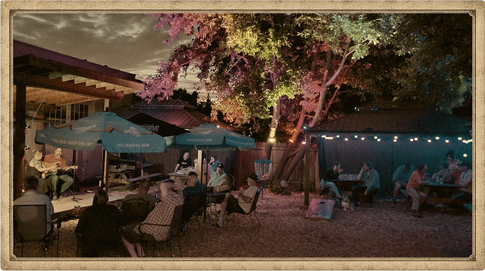 Evening patio at Switchback Saloon — live music on stage, string lights, and friends gathered under the trees